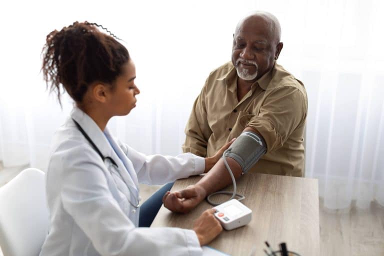 Female doctor taking elderly male patient's blood pressure