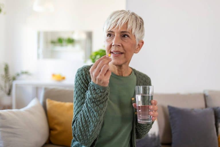 Mature woman taking medication with a glass of water
