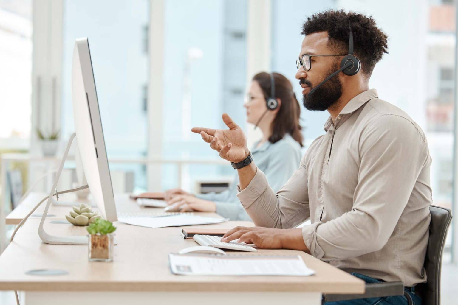 Black insurance agent gesturing at computer while on the phone