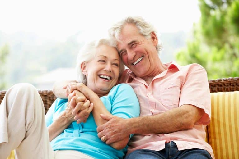Laughing mature couple embracing on a couch outside