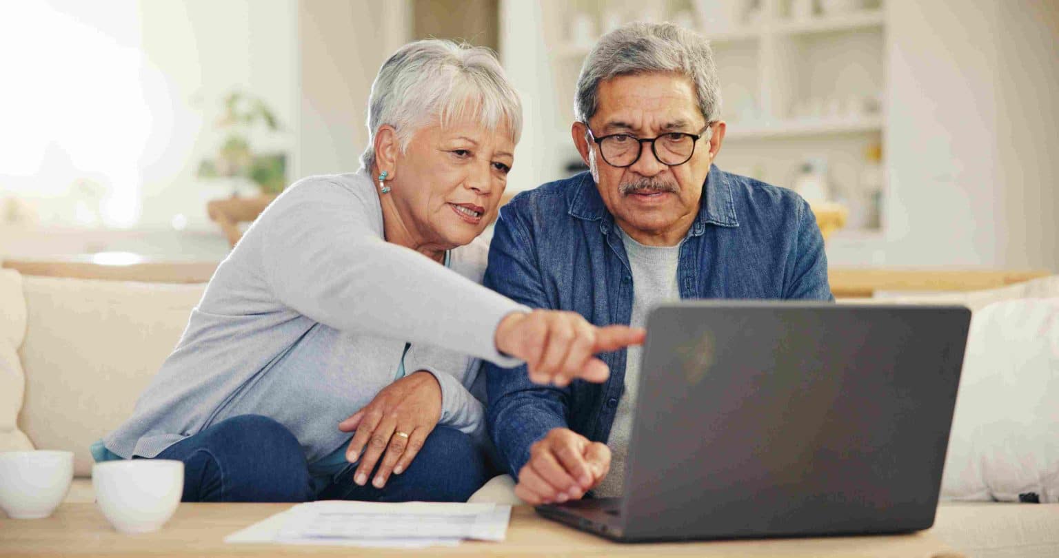 Mature couple talking about insurance options in front of laptop