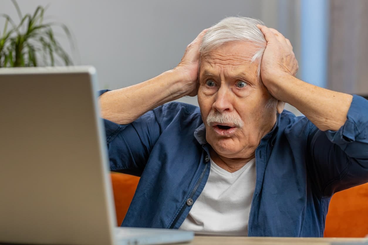 Mature man looking at computer in surprise.
